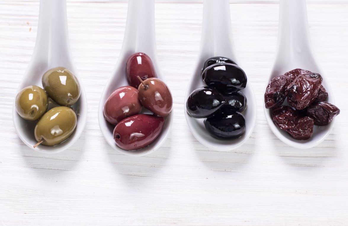 4 kinds of olives in white spoons