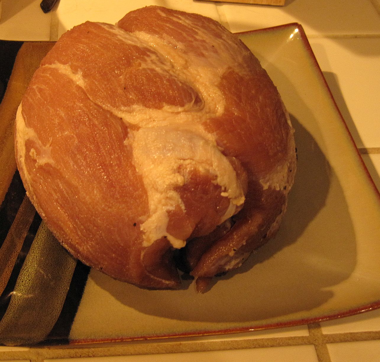 raw brined ham on a plate, ready to cook