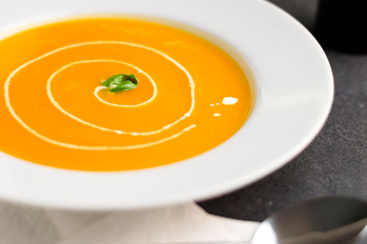 While bowl filled with butternut squash soup topped with a swirl of sour cream