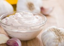 Homemade Aioli (garlic flavored mayo) on wooden background (close-up shot)