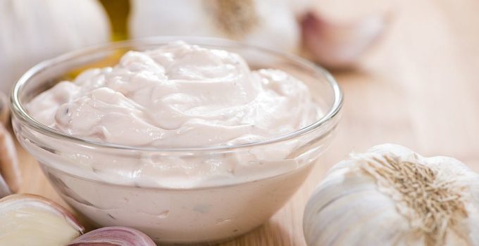 Homemade Aioli (garlic flavored mayo) on wooden background (close-up shot)