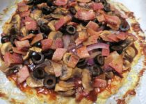 Chicken Crust BBQ pizza is topped with red onions, mushrooms, black olives, and bacon