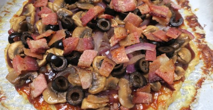 Chicken Crust BBQ pizza is topped with red onions, mushrooms, black olives, and bacon