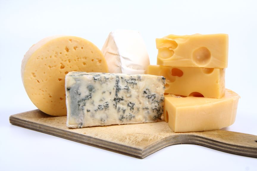 Various types of cheese (swiss, yellow, brie, blue cheese) on cutting board