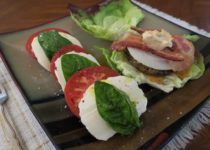 Caprese Salad - Tomato and basil with mozzarella next to a cheeseburger on lettuce leaves