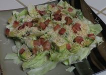 avocado bacon Caesar is iceberg lettuce topped with avocado, Caesar dressing, grated cheese, and bacon bits