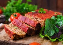 Homemade meatloaf with savory topping on wooden board