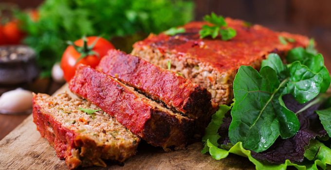 Homemade meatloaf with savory topping on wooden board