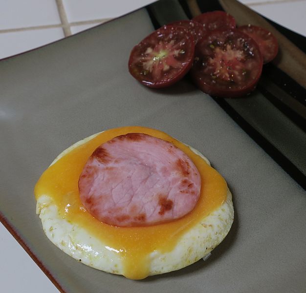 egg stack on a plate with sliced heirloom tomatoes