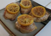 braised lemon pork chops topped with lemon slices on a plate