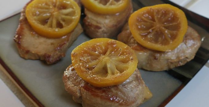 braised lemon pork chops topped with lemon slices on a plate