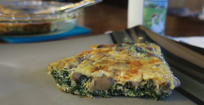 close up slice of spinach mushroom crust-less quiche on a plate