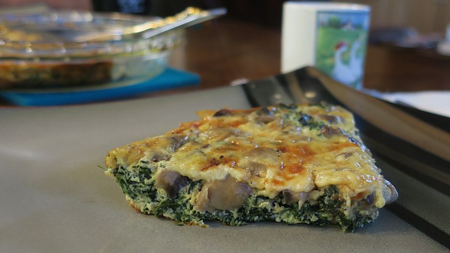 close up slice of spinach mushroom crust-less quiche on a plate