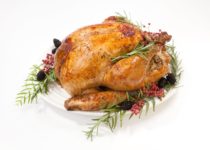 Oven roasted herb turkey on a white plate garnished with fresh herbs