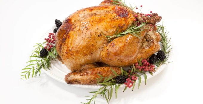 Oven roasted herb turkey on a white plate garnished with fresh herbs